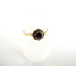 A sapphire and diamond flower head ring, centred with a round mixed-cut untested sapphire, within