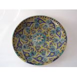 A large eastern pottery charger of circular form with painted stylised in tones of blue, yellow