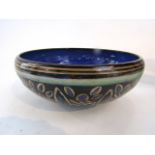 A Royal Doulton bowl with incised and painted stylised leaf decoration on a dark brown ground,