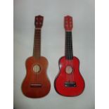 A timber six string Ukulele with red painted finish together with a further four string example (