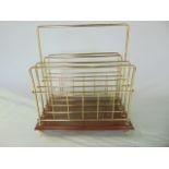 A brass magazine/paper rack raised on a polished timber base with brass feet, height 27cm x 38cm