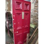 A reclaimed six panelled front door with brass fittings and layers of painted finish