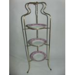 A brass three tier plate stand raised on ball supports (81 cm tall approx)