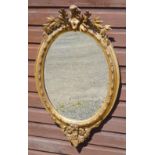 VICTORIAN BEVELLED OVAL WALL MIRROR IN A GILT MOULDED FLORAL AND CABACHON FRAME SURMOUNTED BY A