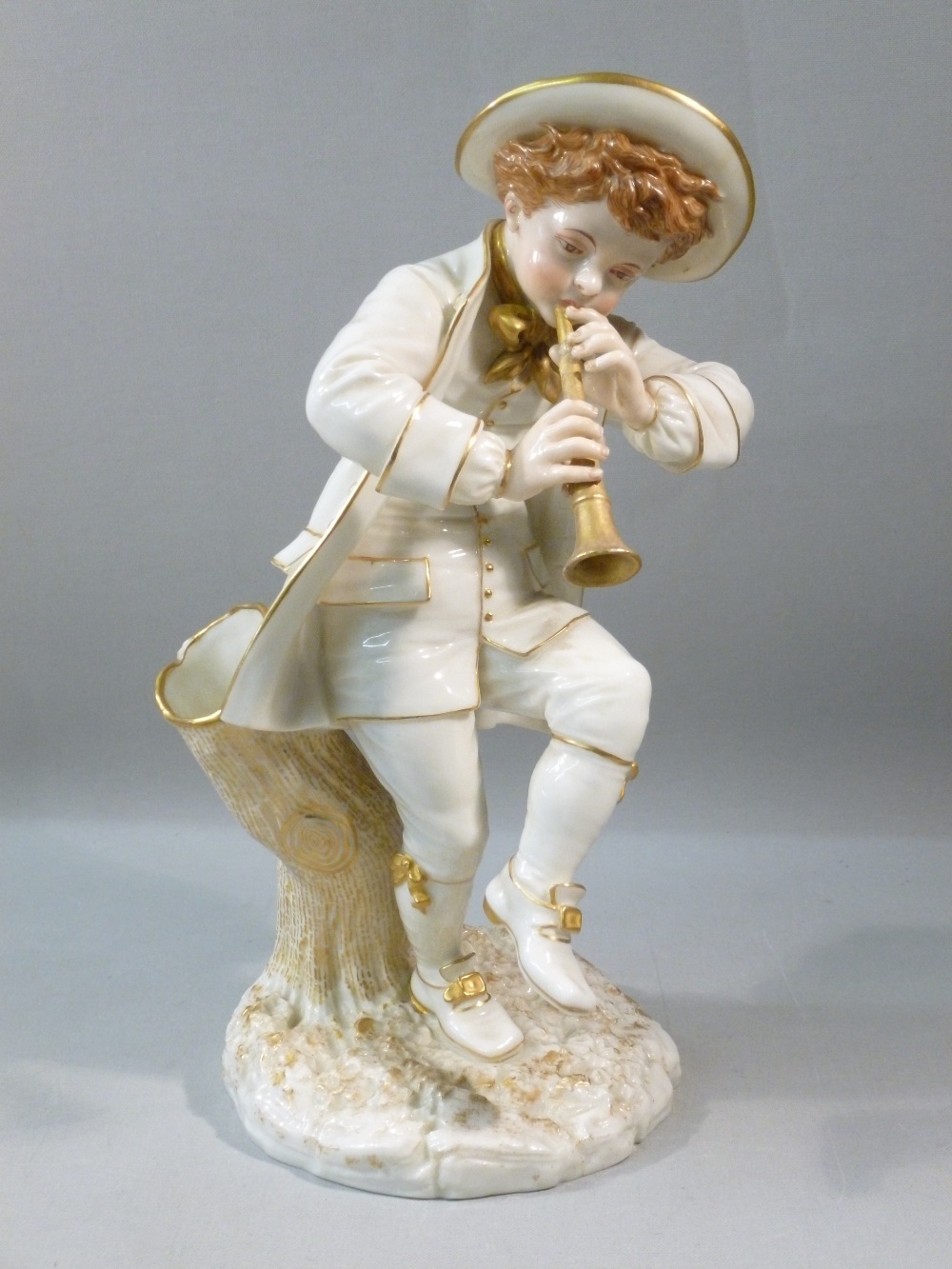 VICTORIAN HADLEY WORCESTER PORCELAIN FIGURE OF A YOUNG MAN PLAYING A FLUTE, STANDING AGAINST A