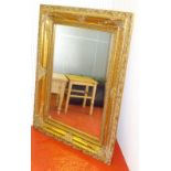 BEVELLED RECTANGULAR WALL MIRROR IN A GILT FLORAL FRAME (92 cm x 122.5 cm)