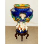 ITALIAN MAJOLICA STYLE URN WITH RAM'S HEAD AND FRUITING SWAG DECORATION ON FOUR PUTTI SUPPORTS (48