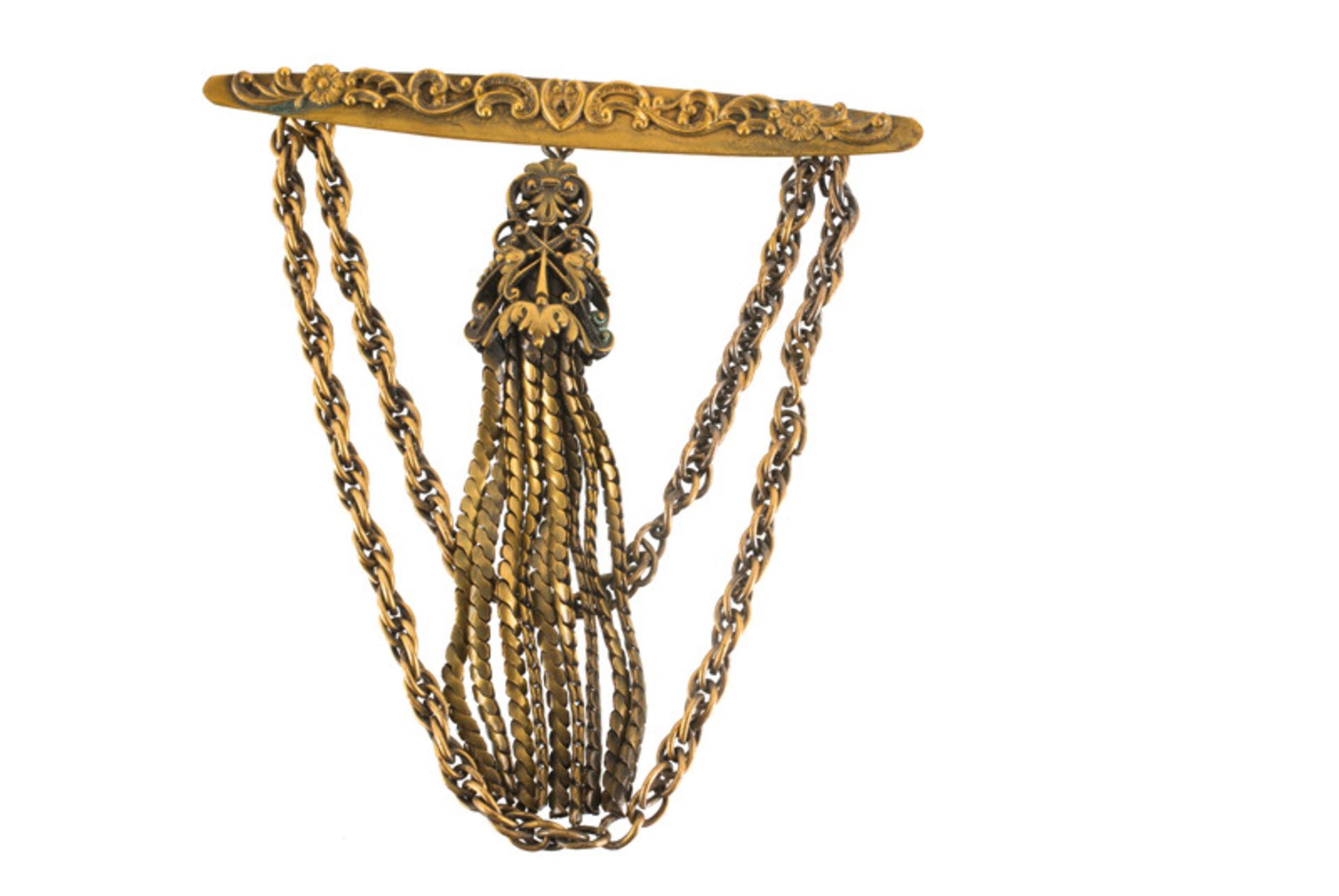 A Joseff Hollywood goldtone brooch with two chains and a pendant, decorated with scroll motifs.
