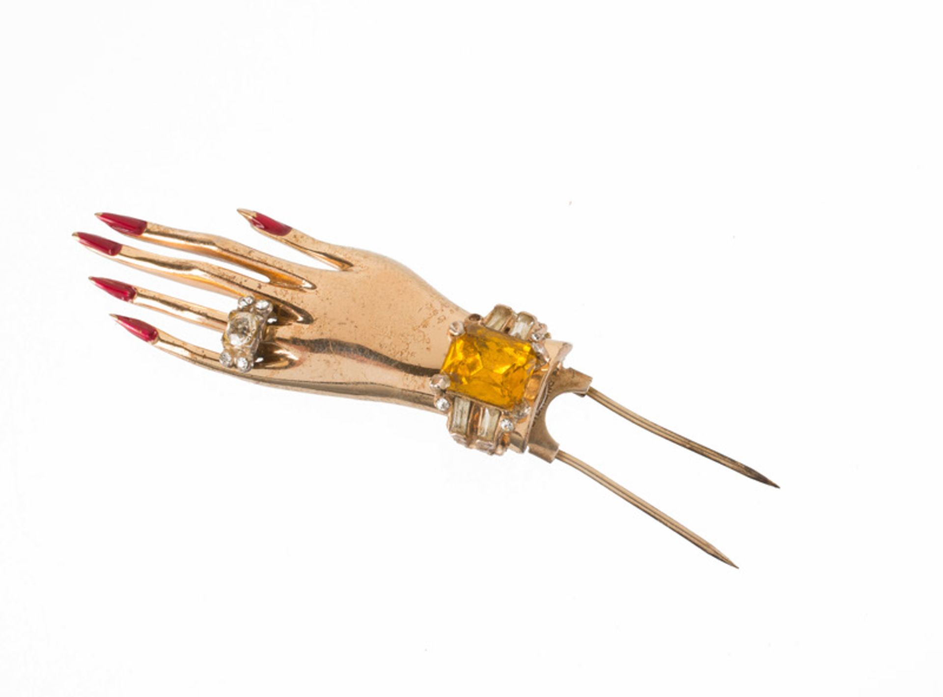 A Coro sterling goldtone brooch in the shape of a hand, wearing a ring. Set with yellow stones,