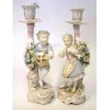 A PAIR OF CONTINENTAL FIGURAL CANDLESTICKS, LATE 19TH CENTURY the young boy carrying a basket, his