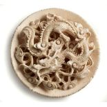 A CHINESE CARVED IVORY CIRCULAR PANEL, MEIJI, 1868-1912 carved in high relief with a dragon
