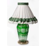 A GREEN CUT-GLASS TABLE LAMP the fabric shade above a floral cut-glass pattern body, on a circular