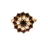 A GARNET AND SEED PEARL RING of flower-head form, set with round garnets and seed pearls, in 18ct