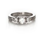 A DIAMOND RING centred with a claw-set brilliant-cut diamond weighing approximately 0.34cts, flanked