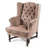 AN UPHOLSTERED WINGBACK ARMCHAIR the button-back between padded close-nailed sides, padded arms,