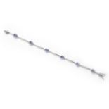 A TANZANITE AND DIAMOND BRACELET designed as a series of curved bar links alternating with claw-