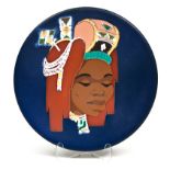 A KALAHARI PLATE painted with an African woman wearing a traditional headdress against a dark blue