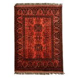 AN AFGHAN RUG, MODERN the red field with two star medallions and geometric shrubs, within a red-