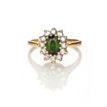 A TOURMALINE AND DIAMOND RING claw set to the centre with an oval mixed-cut green tourmaline