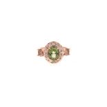 A TOURMALINE AND DIAMOND RING centred with an oval mixed-cut green tourmaline weighing approximately