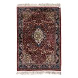 AN INDO-PERSIAN RUG, MODERN the dark red field with a green and ivory floral medallion, beige