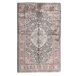 AN INDO-PERSIAN SILK CARPET, MODERN the black field with an ivory floral medallion, madder spandrels