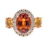 A SPESSARTITE GARNET, DIAMOND AND YELLOW SAPPHIRE RING claw-set to the centre with an oval mixed-cut