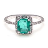 AN EMERALD AND DIAMOND RING centred with a square emerald-cut emerald weighing approximately 1.
