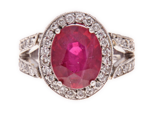 A RUBY AND DIAMOND RING claw-set to the centre with an oval mixed-cut fracture filled ruby