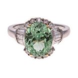 A TSAVORITE AND DIAMOND RING centred with an oval mixed-cut tsavorite weighing 3.22cts, flanked on