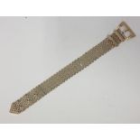 A 9CT GOLD BRACELET comprised of nine rows of brick links, with an adjustable buckle clasp