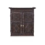 AN OAK SPICE CUPBOARD, LATE 17TH/EARLY 18TH CENTURY the outswept cornice above a carved frieze, a