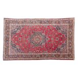 A KESHAN CARPET, PERSIA, MODERN the red field with a floral dark blue medallion, similar spandrels