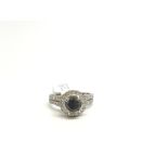 Black diamond cluster ring, central 5.6mm black diamond, set within a cluster of brilliant cut white