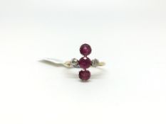 Ruby and diamond ring, three round cut rubies vertically set, a single old cut diamond to each