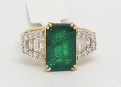 Emerald and diamond ring, central step cut emerald weighing an estimated 2.65cts, with three