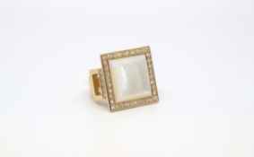 A large mother of pearl and diamond dress ring. The square mother of pearl surrounded by a halo of