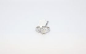 Diamond Ring. The central emerald cut weighing 0.88cts with a further 0.33cts of diamond accents.