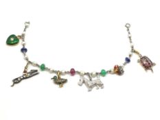 A white metal charm bracelet (tested as platinum) set with sapphires, emeralds, rubies and pearls.