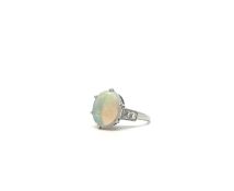 A diamond and opal ring. The central opal set in white metal testing as gold. Each shoulder set with