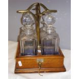 A Chapman Patent 'The Janitor' oak and brass tantalus, no. 765, composed of four cut glass decanters