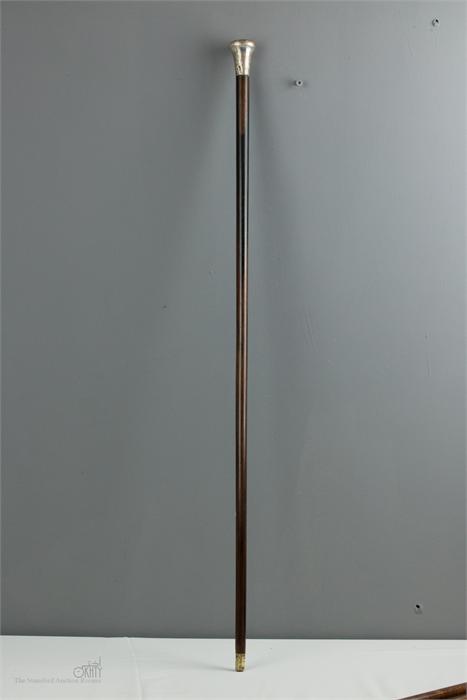 A walking cane with silver top, engraved with decoration.