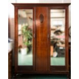 An Edwardian mahogany double wardrobe with inlaid decoration and two mirrored doors.