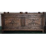 An oak carved coffer with two panel front carved with stylised foliate decoration.