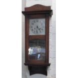 A 1930s oak cased wall clock with Arabic dial and pendulum.