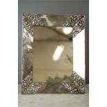 A white metal table mirror, marked 900, the wide frame bearing embossed floral panels to the