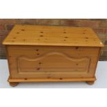 A pine blanket chest with carved front panel and a bed pan.
