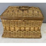 A wicker sewing box of sarcophagus form containing tins of pins, a brush set etc.