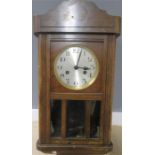 A 1930s oak cased wall clock with pendulum.