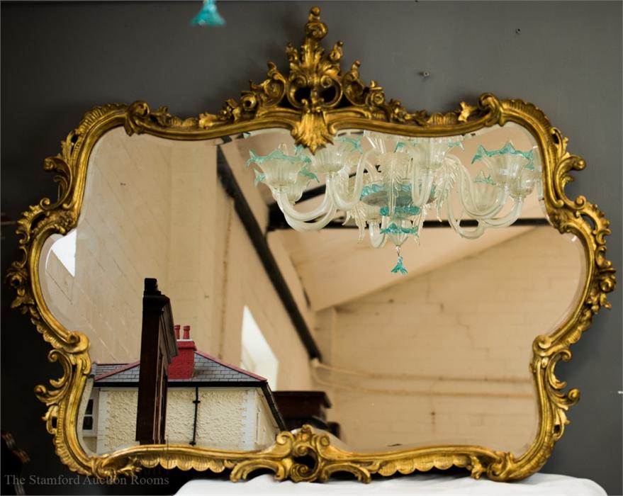 A giltwood wall mirror with Rococo style scrollwor